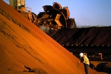 A worker inspects iron ore stockpiles at Marandoo, in Western Australia's Pilbara.