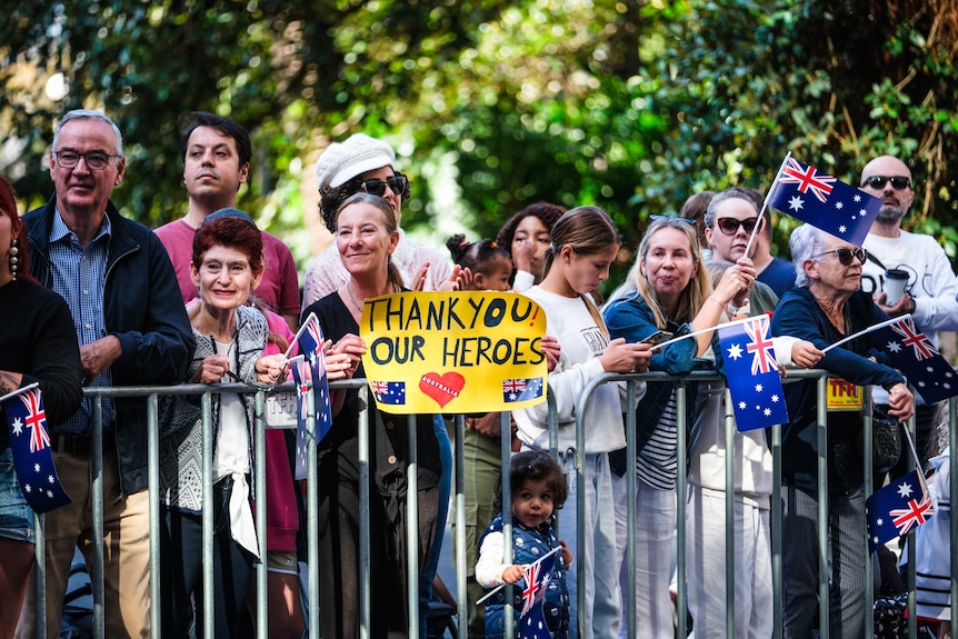 A woman holds a sign that says 'thank you our heroes'