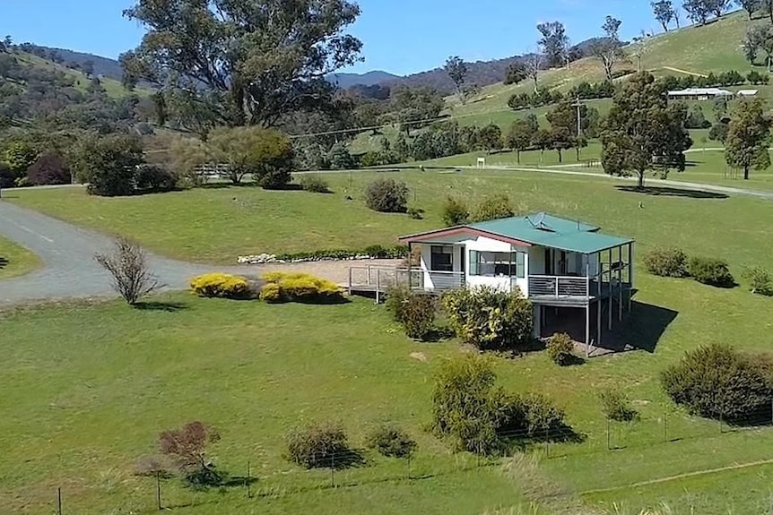 Aerial view of a cottage surrounded by lawn and trees