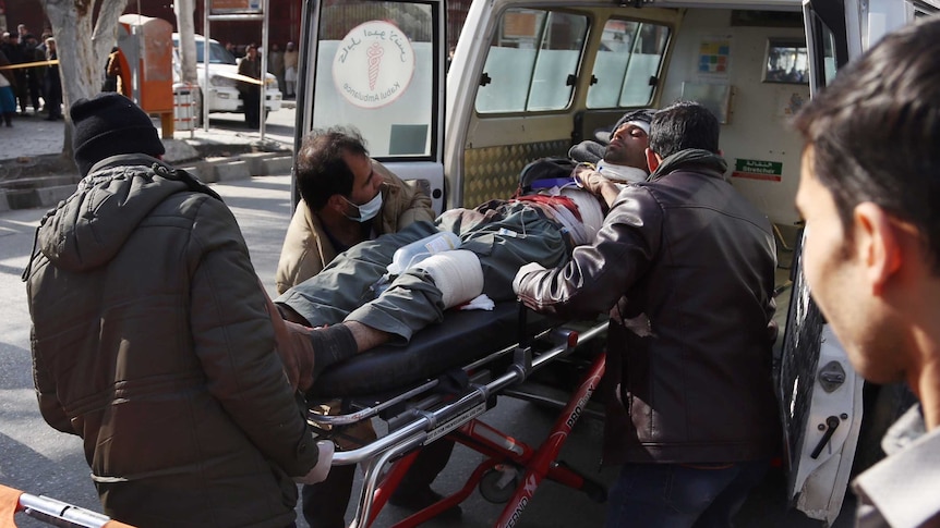 People help carry an injured man on a stretcher to the hospital following a suicide attack in Kabul