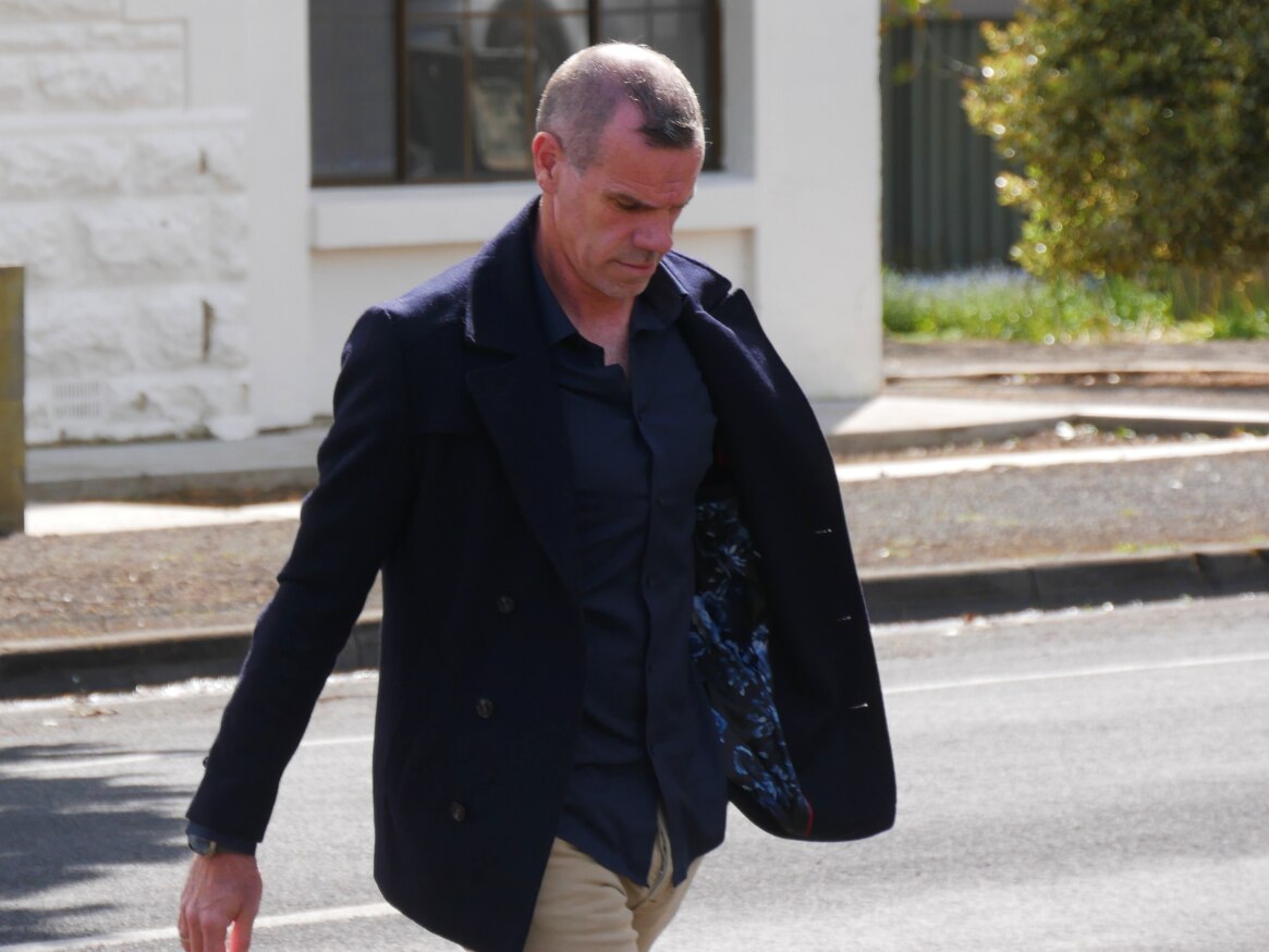 A man with short grey hair wearing a dark blue jacket and shirt