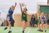two girls jumping for a ball on a netball court