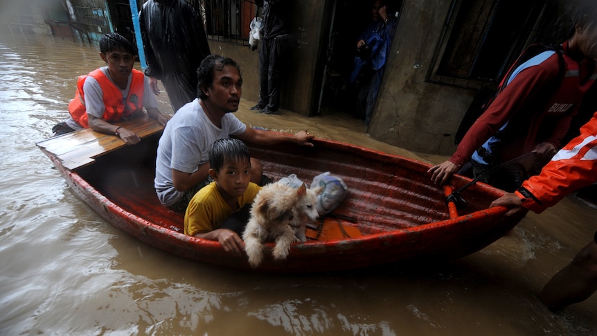 Residents ride a boat as they evacuate a flooded area during typhoon Nesat in San Mateo, Rizal, east of Manila