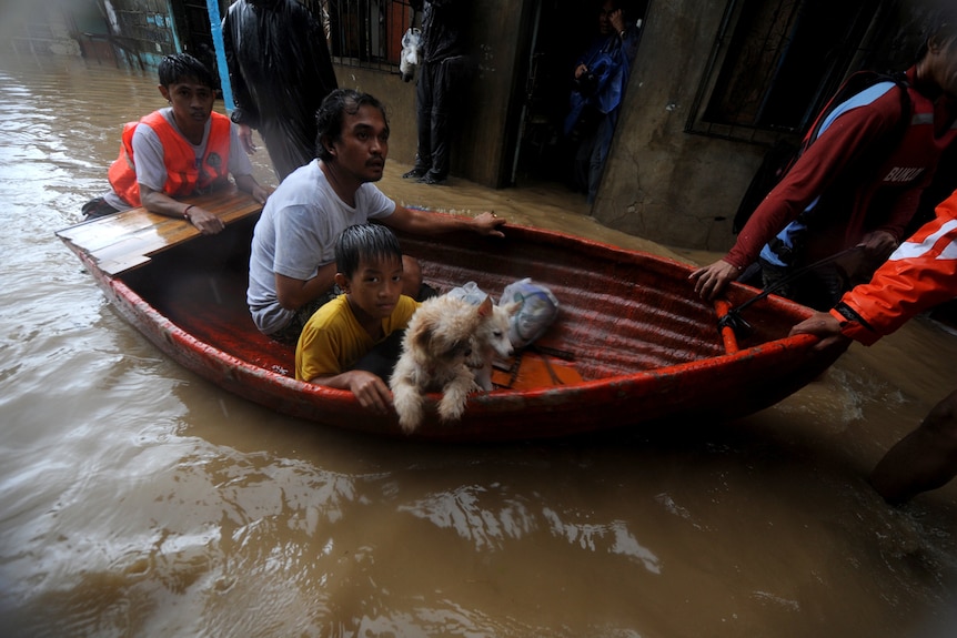 Residents ride a boat as they evacuate a flooded area during typhoon Nesat in San Mateo, Rizal, east of Manila