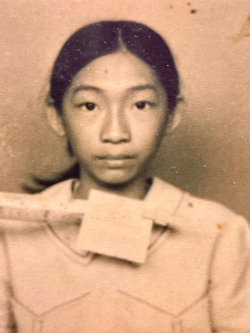 Old sepia photo of a young Asian girl with her hair in a ponytail.