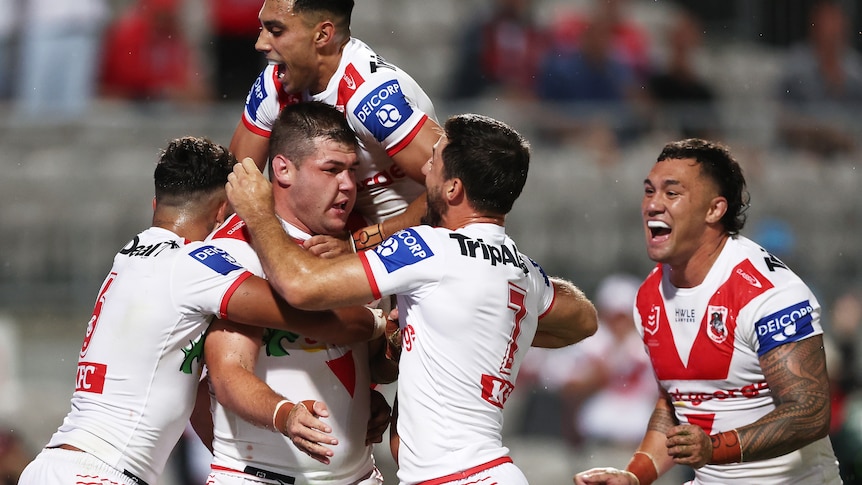 A man is mobbed by his teammates after scoring a try