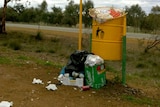 Over-flowing litter bin by a roadside.