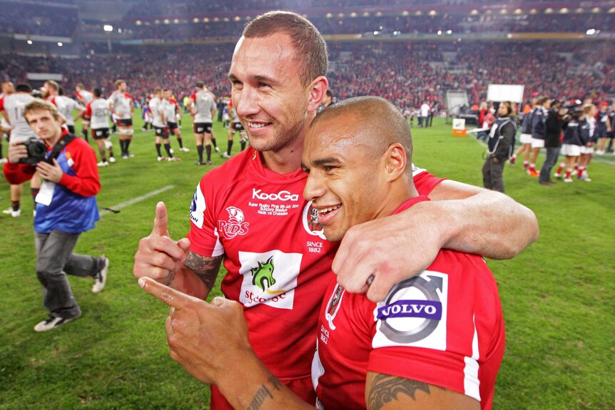 Quade Cooper and Will Genia embrace as they each hold up a finger for photographers.