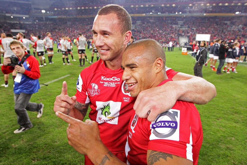 Quade Cooper et Will Genia s'embrassent alors qu'ils tendent chacun un doigt pour les photographes.