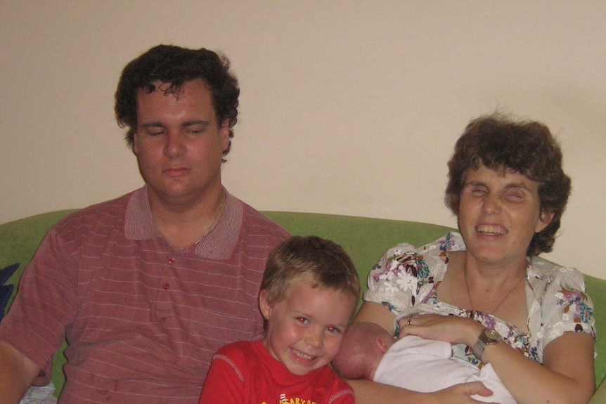 Emma and Vaughn Bennison sitting on a couch with their then-toddler Julian and baby Lucy to depict parenting with a disability.