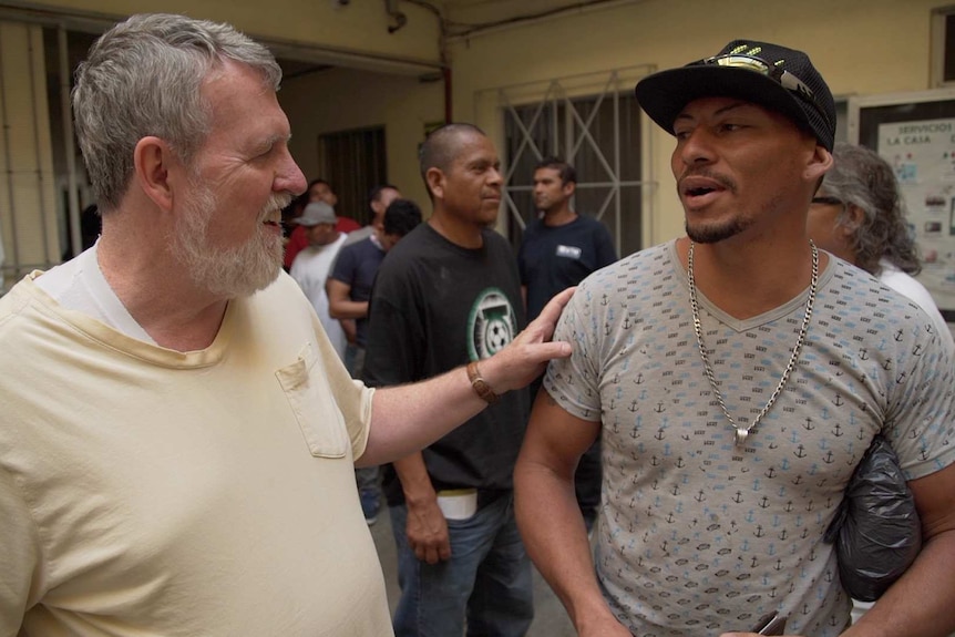 Father Patrick Murphy talks to a recently arrived Honduran migrant at the Casa De Migrante shelter.