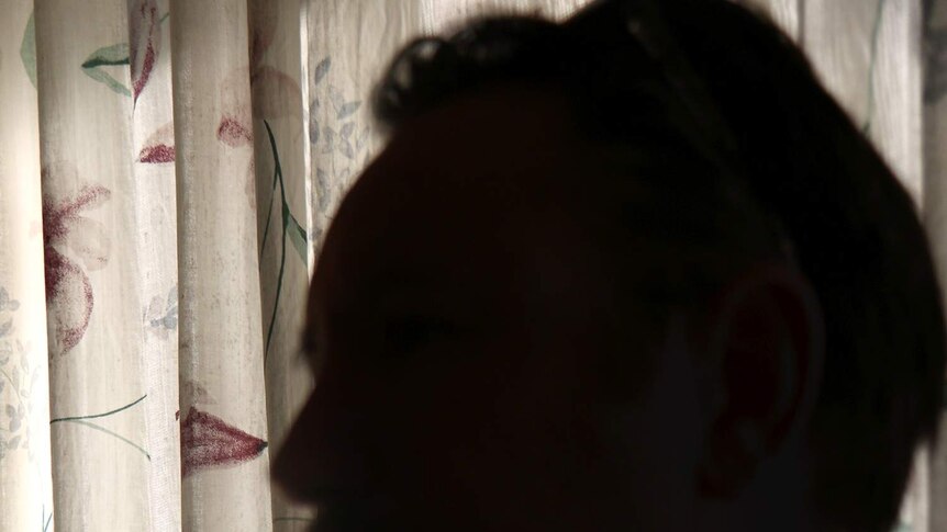 An unidentified photo of a youth worker who cares for troubled teens with a curtain behind him