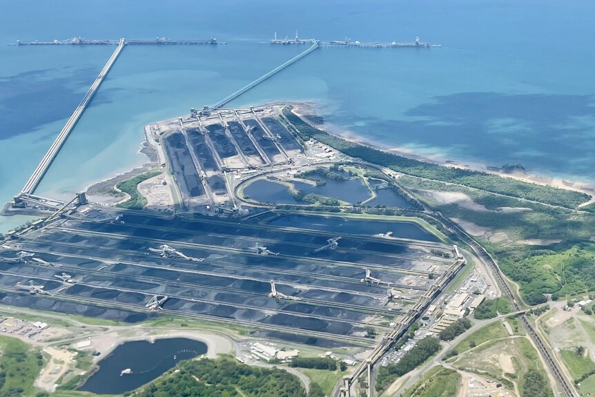 An aerial photo of a coal loading sea terminal, with to large jetties and a number of stockpiles.
