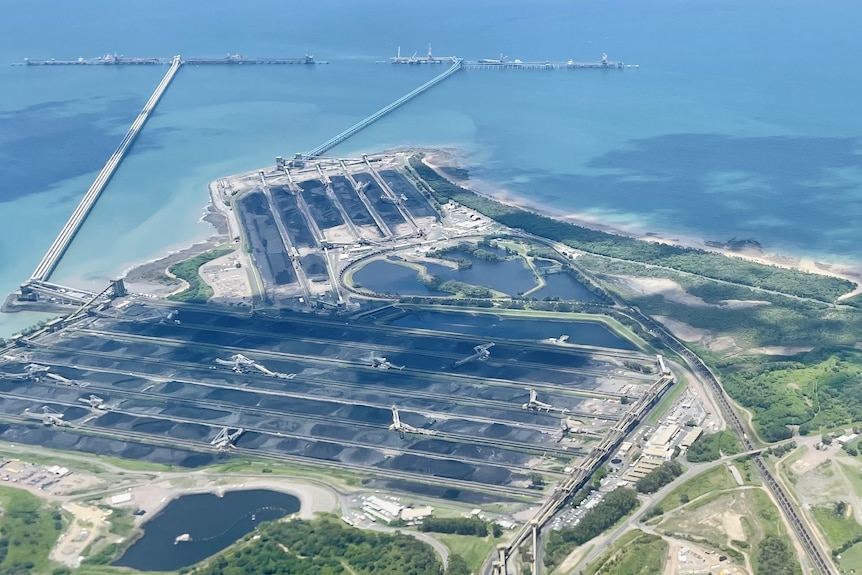 An aerial photo of a coal loading sea terminal, with to large jetties and a number of stockpiles.