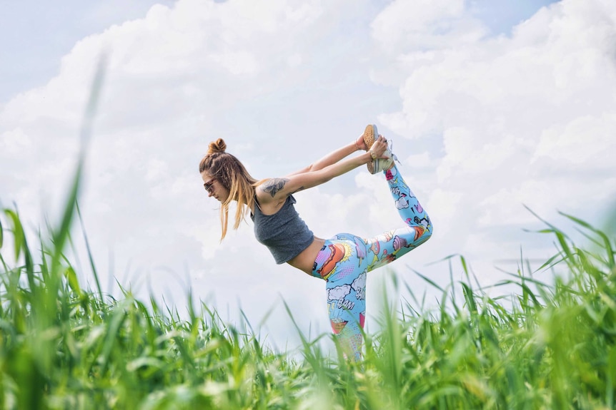 A woman does yoga in a field