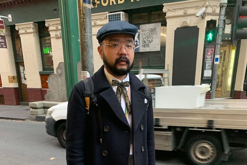 一名戴贝雷帽的亚裔男性站在墨尔本街头。