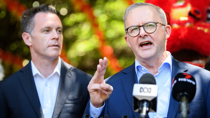 a man wearing glasses standing in front of the press with another man standing next to him