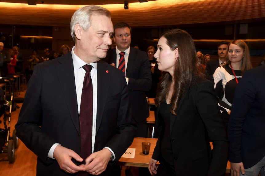 Finnish politicians Antti Rinne and Sanna Marin look at each other at a ministerial event.