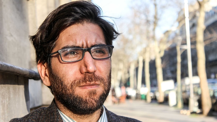 Portrait of Omar standing in the street.