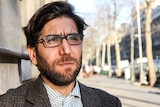Omar, a young man with dark hair, beard and glasses.