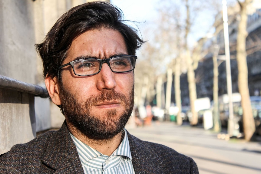 Portrait of Omar standing in the street.