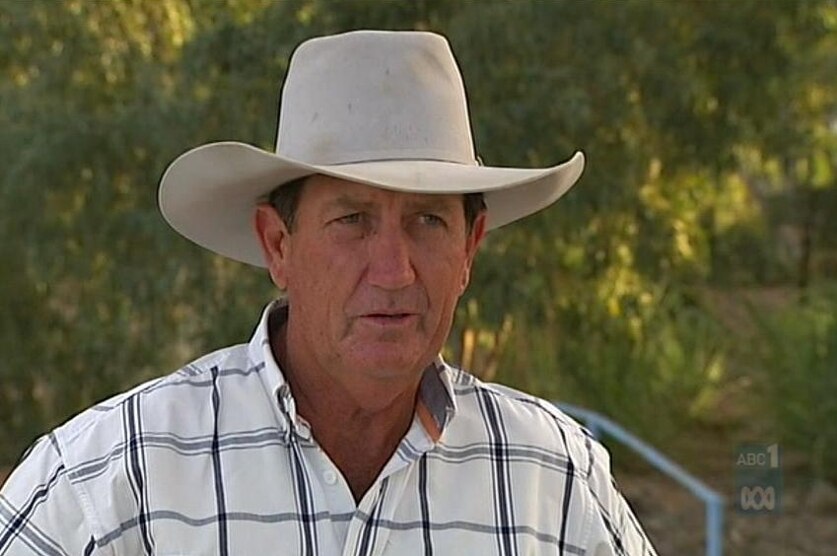 A late middle-aged man in a white stetson hat and a light shirt with wide checks.