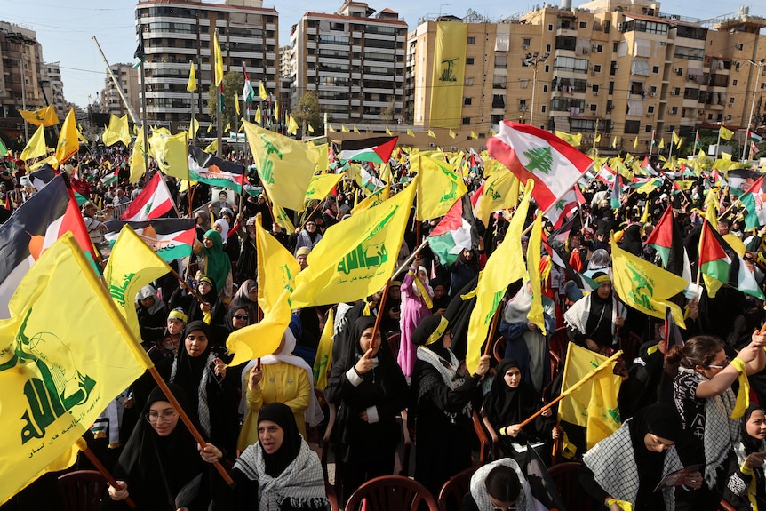 Supporters of Hezbollah gather waving yellow flags and the flag of Lebanon in Beirut
