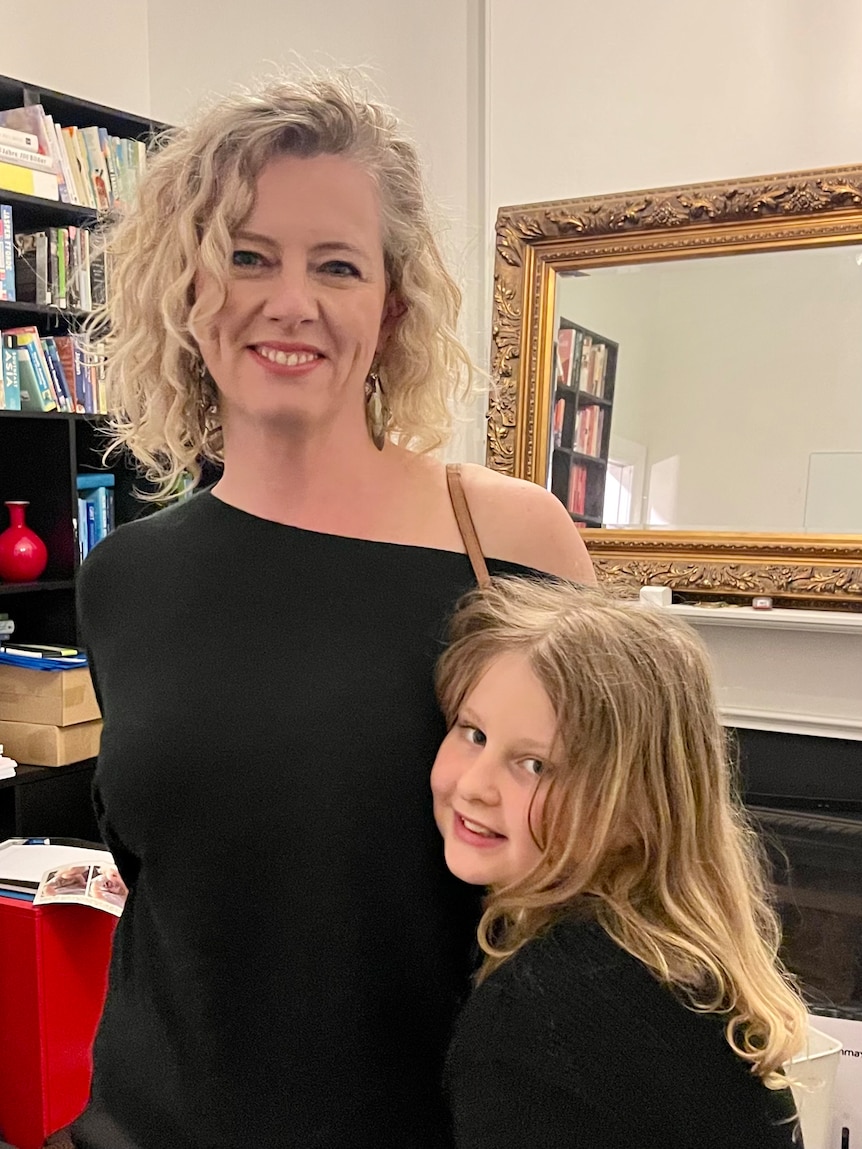 Blonde woman standing with her young daughter.