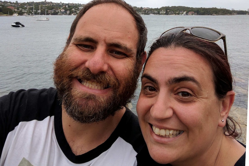 Dean and wife smile while standing in front of water, for a story about perinatal depression and anxiety in men.