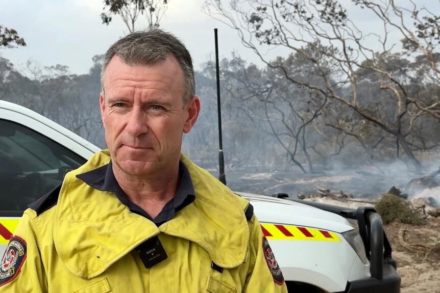A firefighter speaking to media at scene of bushfires.  