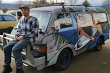 A man sits on the boot of his van at the claypits carpark.