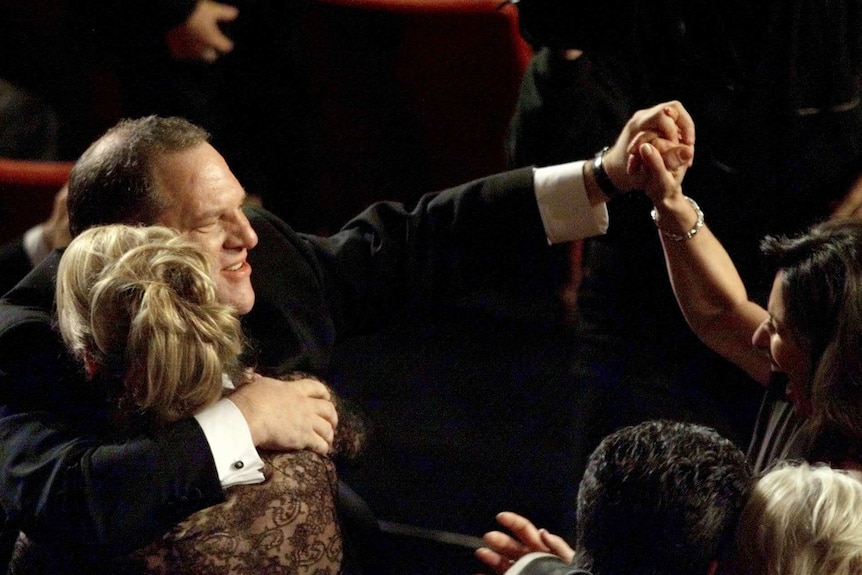 Harvey Weinstein, wearing a suit, hugs a person at the Oscars.