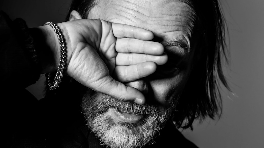 black and white portrait of Thom Yorke holding his right hand up over his face