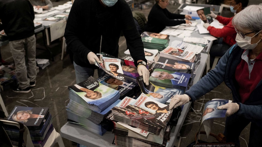 french volunteers sorting stacks of flyers featuring various presidential candidates