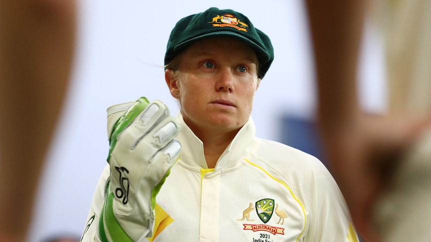 Alyssa Healy is pictured in a baggy green, whites and wicketkeeping gloves