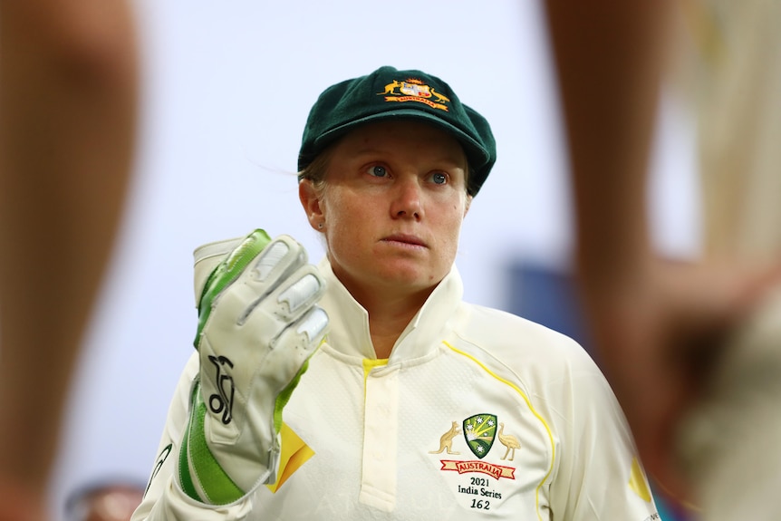 Alyssa Healy is pictured in a baggy green, whites and wicketkeeping gloves