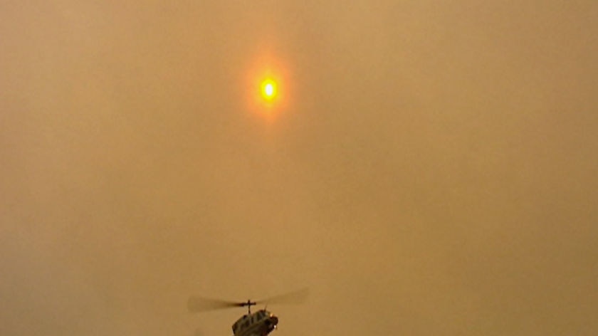 A helicopter waterbombing a bushfire.