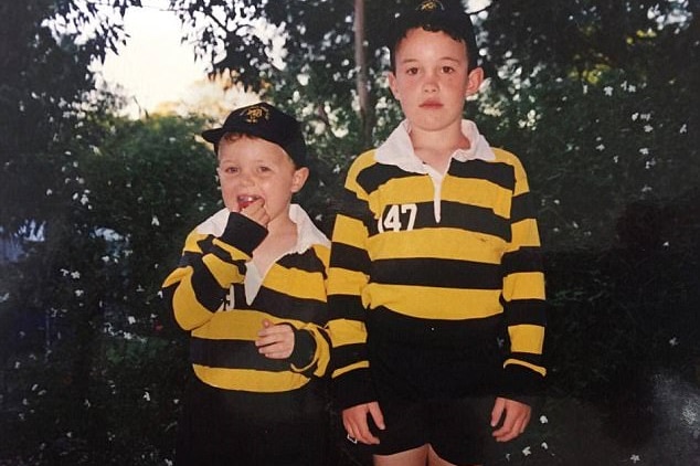 Two boys in rugby uniforms pose for the camera.