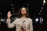 Gina Haspel holds one hand in the air as she is sworn in.