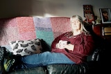 Woman sitting on a couch holding a mug.