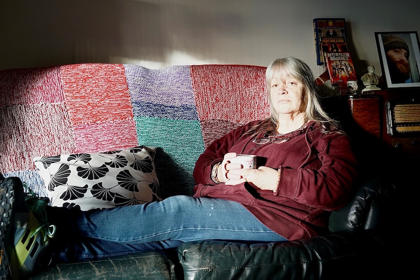 Woman sitting on a couch holding a mug.