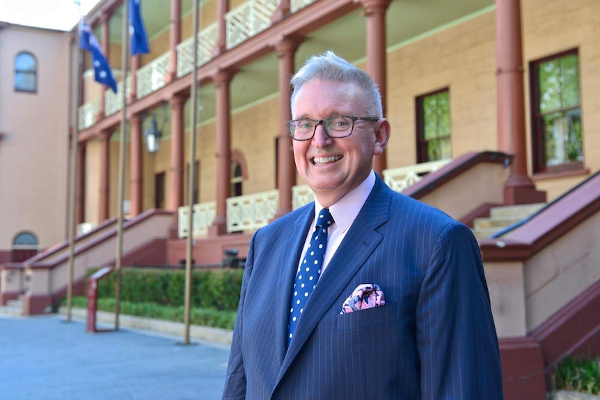 An older man smiling outside an office