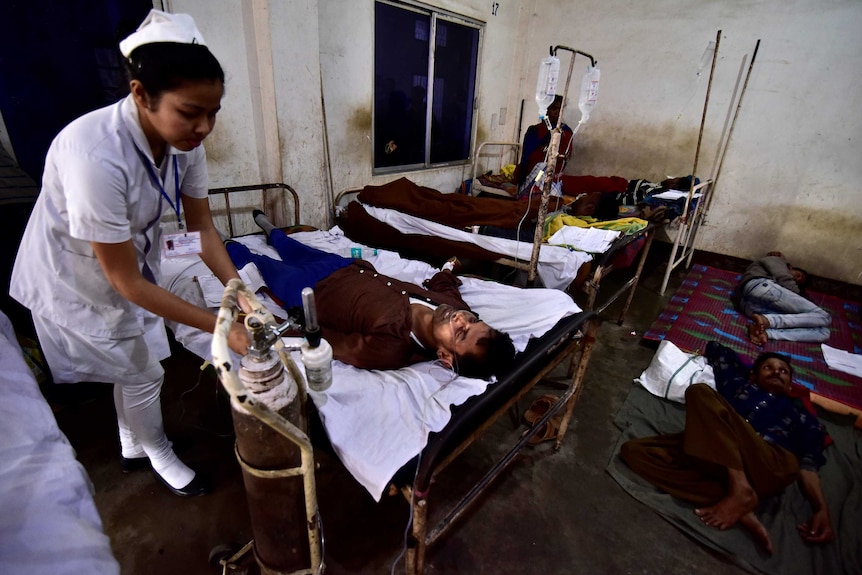 paramedic with victims lying on beds who consumed bootleg liquor