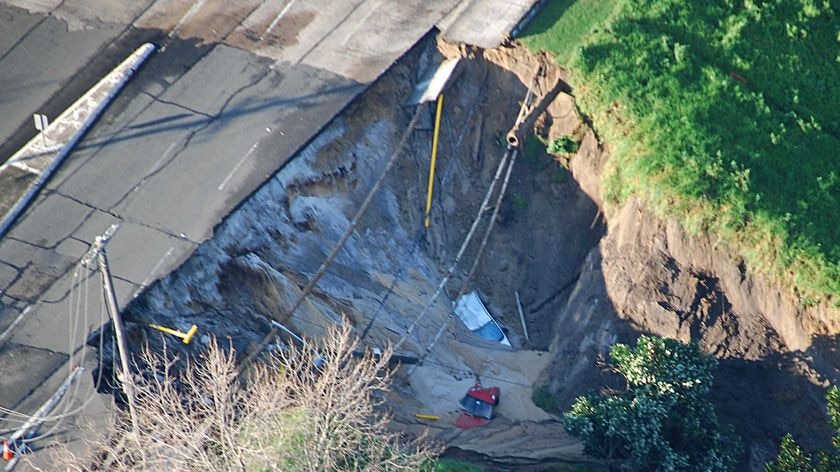 Cars sit in the landslide left after a ruptured water main left a 25-metre wide crater.