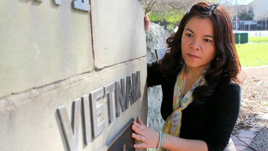 Teresa Tran looks at the word Vietnam inscribed into stone on the war memorial at MacCabe Park, Wollongong