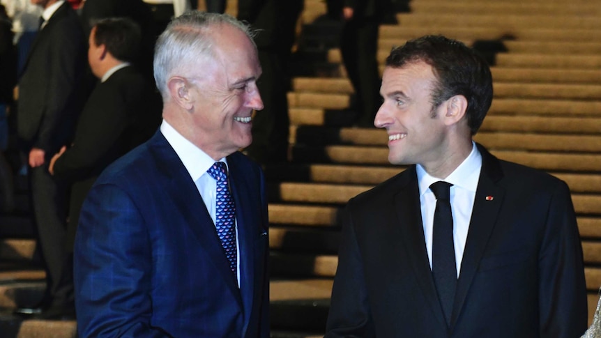 Malcolm Turnbull and Emmanuel Macron look at each other as they shake hands on a set of wide concrete steps