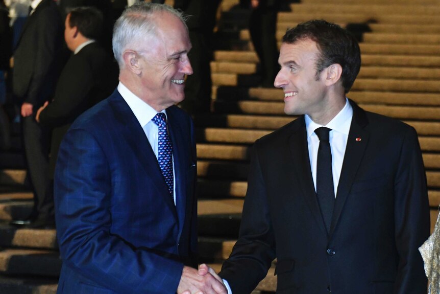 Malcolm Turnbull and Emmanuel Macron look at each other as they shake hands on a set of wide concrete steps