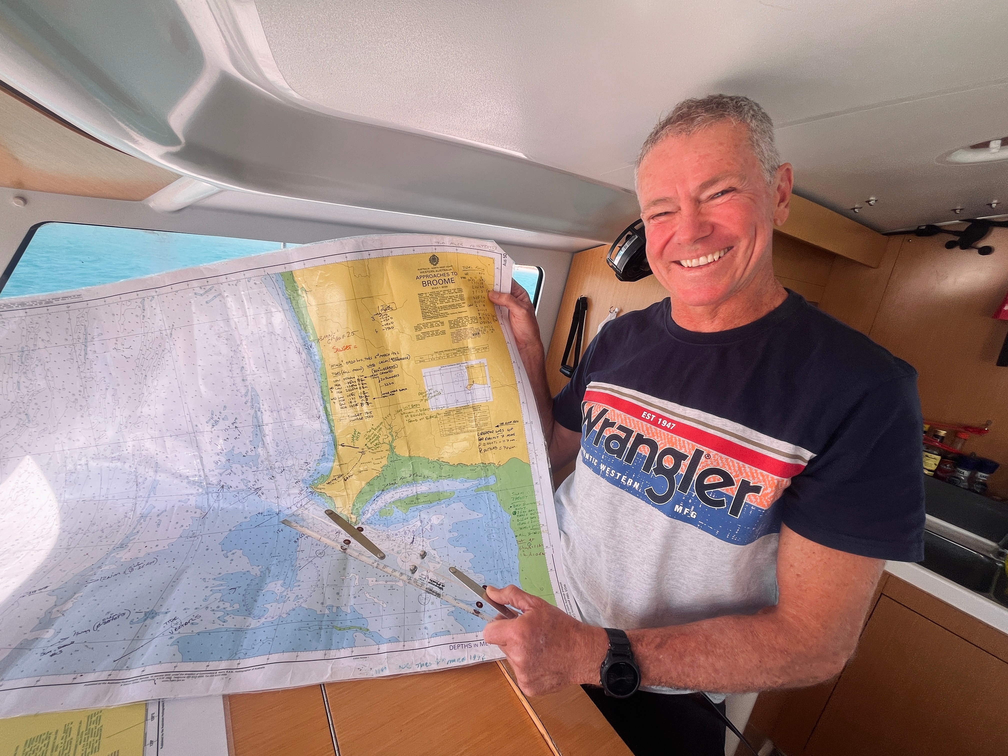 A man stands smiling and pointing at a nautical map.