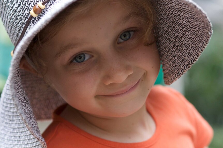 A portrait of a little girl wearing a wide brim hat