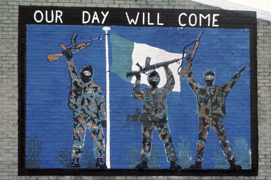 a painting of IRA militants holding rifles with the words "Our Day Will Come" above them